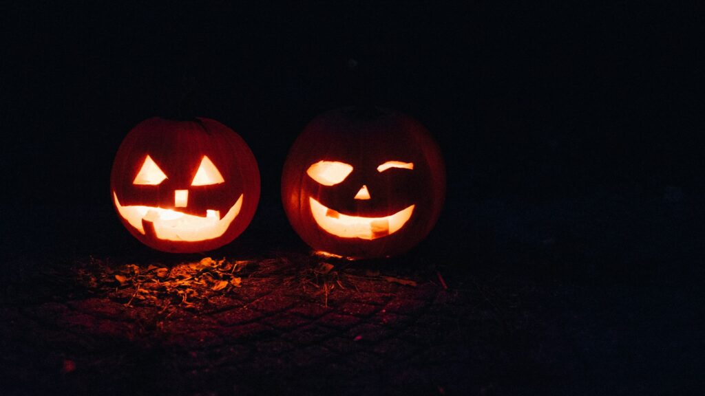 Zwei grinsende Jack O'Lanterns leuchten im Dunkeln.