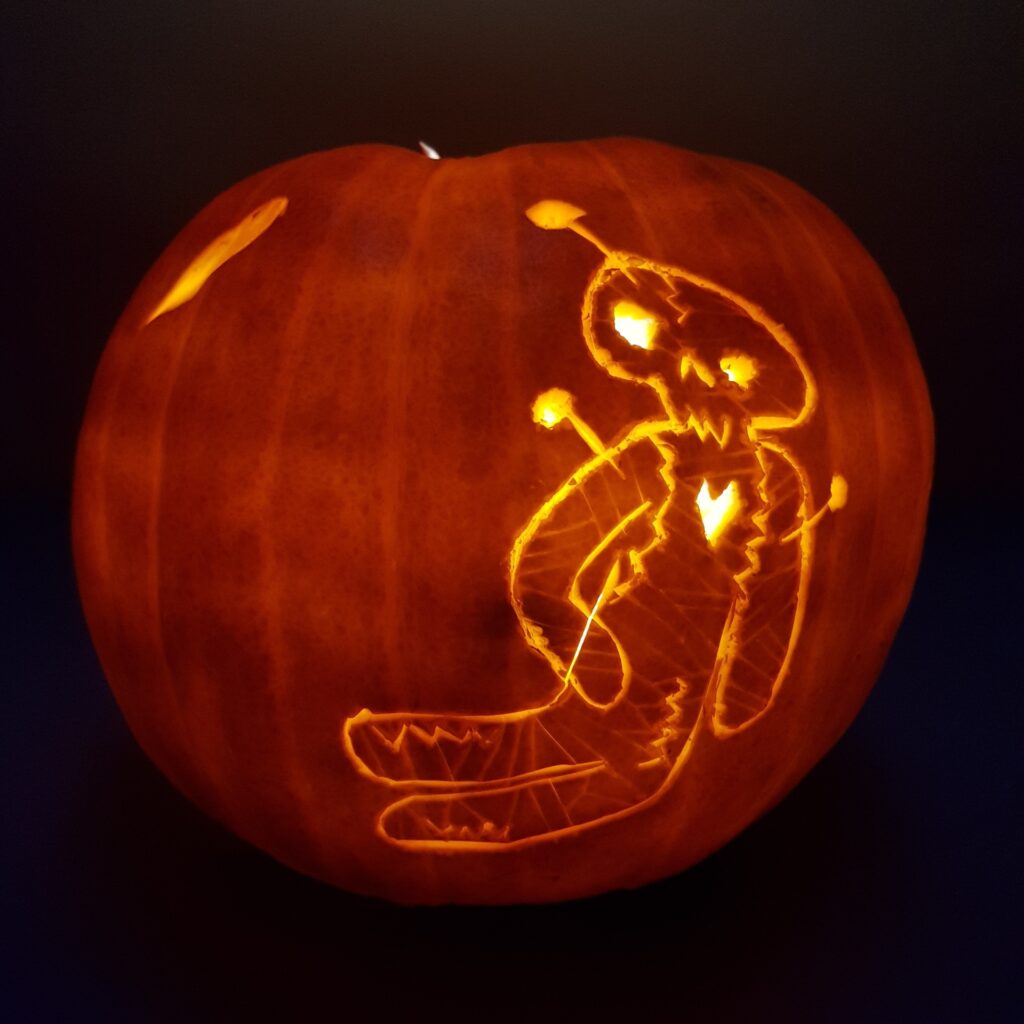 Jack O'Lantern in den der Umriß einer Voodoopuppe geritzt wurde leuchtet im Dunkeln.